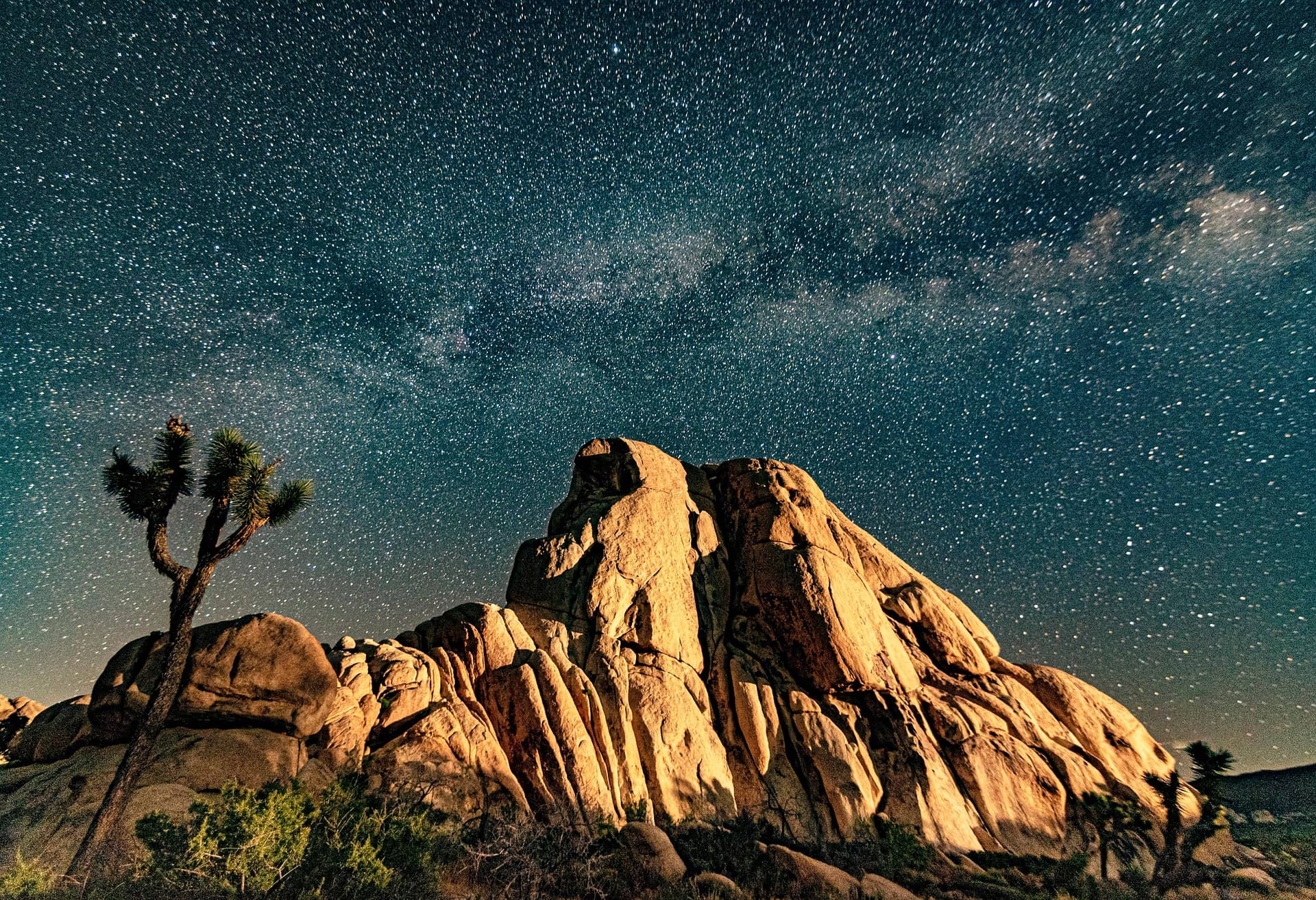 Moonlit granite boulders and a Joshua tree beneath the Milky Way