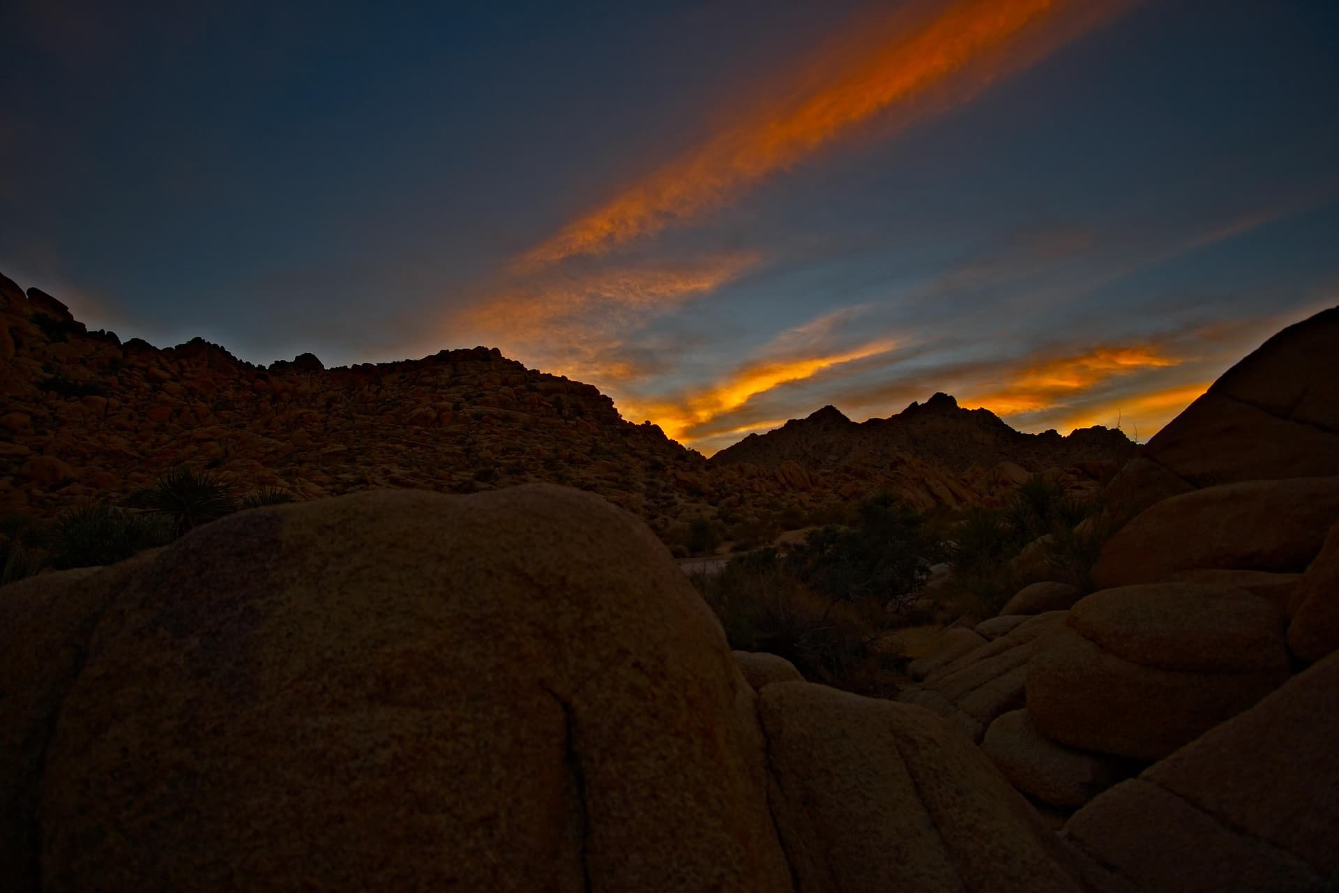 Granite boulders in the Joshua Tree desert beneath a burning sunset sky